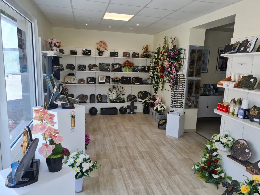 Intérieur de la boutique funéraire présentant des plaques, urnes et fleurs de deuil