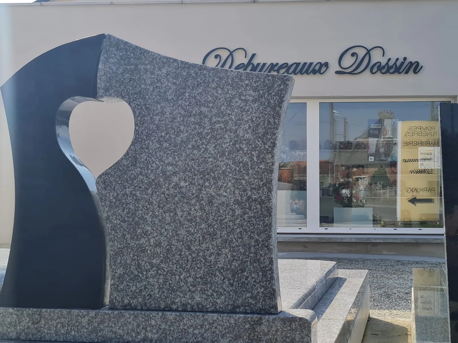 Stèle funéraire bicolore sculptée d'un cœur devant l'agence Debureaux Dossin