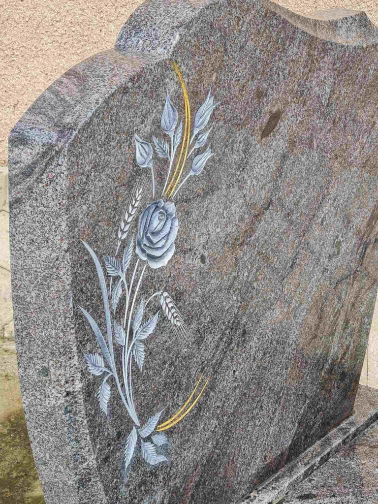 Gros plan sur une stèle en granit sculptée d'un motif de rose et d'épis de blé
