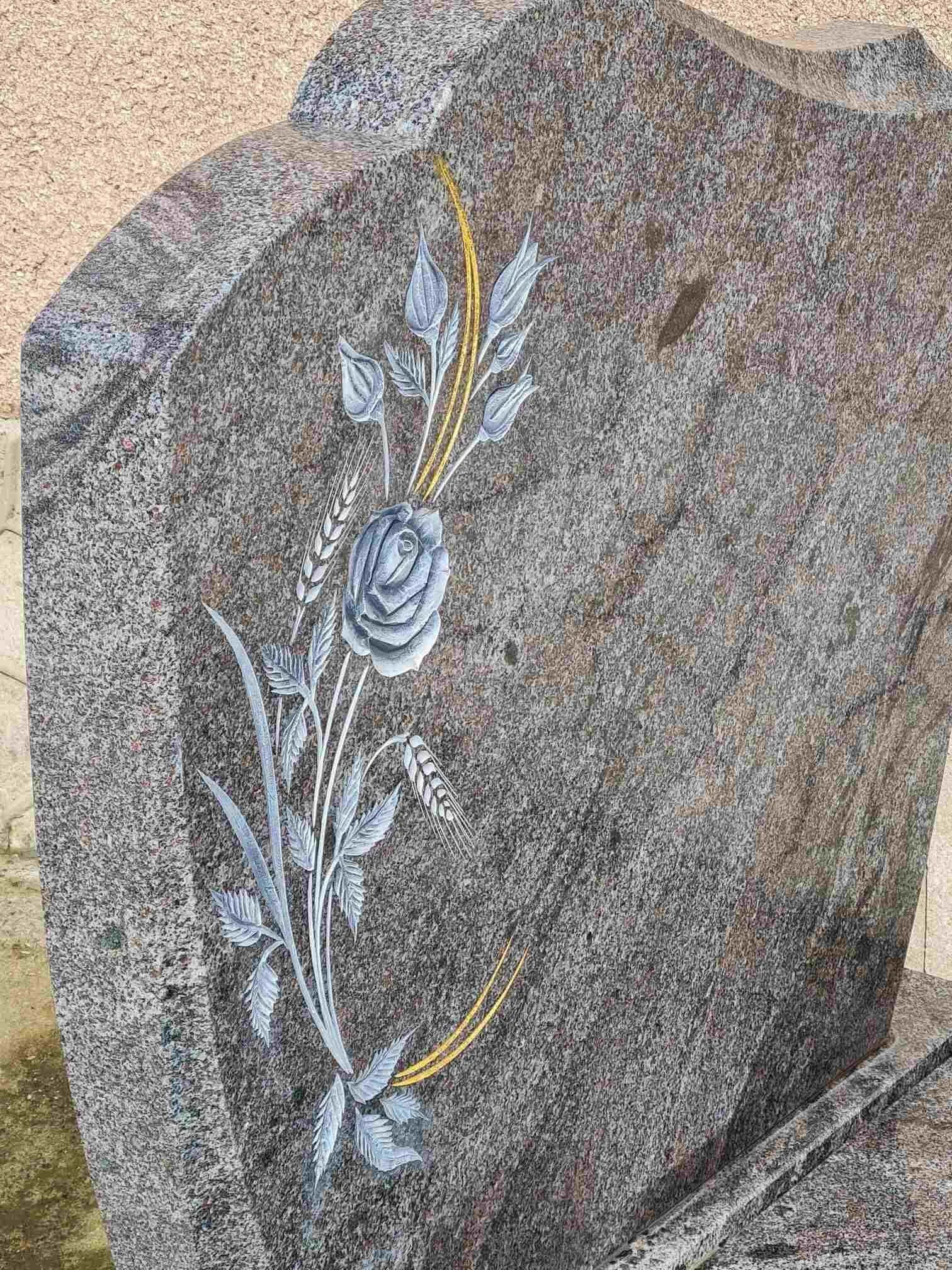 Gros plan sur une stèle en granit sculptée d'un motif de rose et d'épis de blé