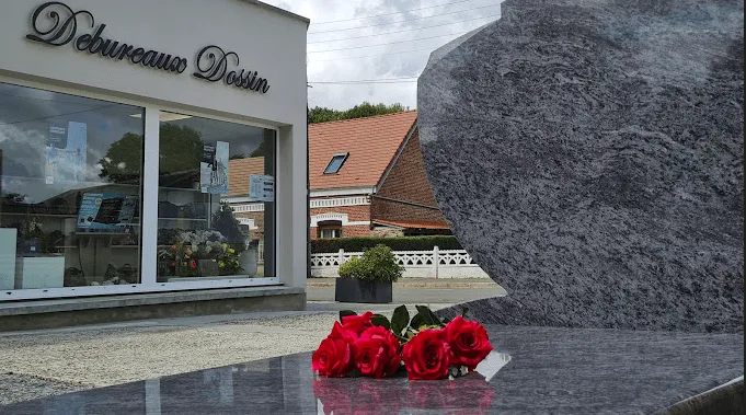 Bouquet de roses rouges posé sur une stèle funéraire en granit sombre devant l'agence
