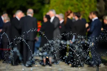 Foule de proches en tenues sombres rassemblés lors d'une cérémonie de deuil