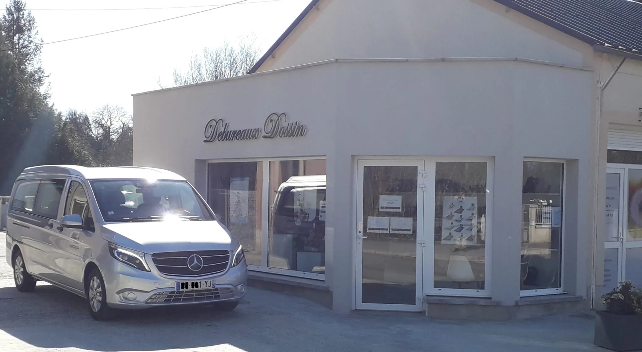 Vue rapprochée de la devanture de l'agence Debureaux Dossin avec son véhicule de transport